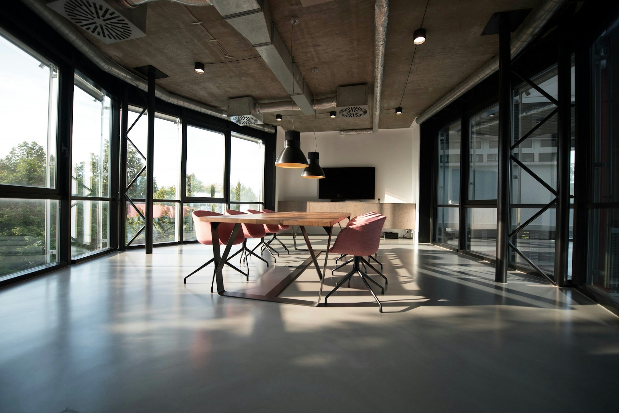 Sunlit contemporary workspace with glass partitions, a meeting table, and architectural finishes